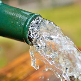 A close up of clear water pouring out of an outdoor spigot
