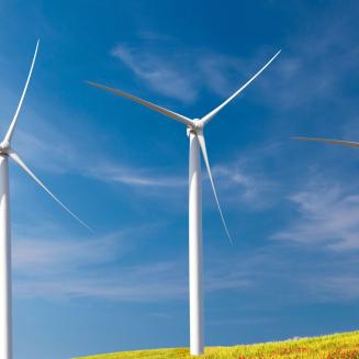 Three windmills on a ridge with a clear blue sky behind them