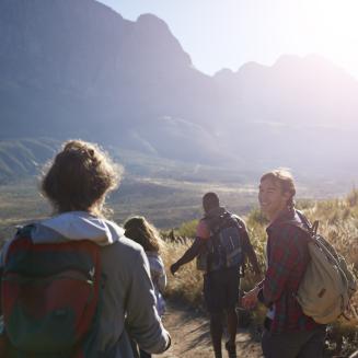 A group of people walking down a sunny path towards mountains