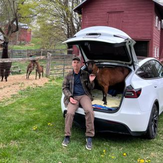 Farmer Robert McKeon with a goat inside his Tesla
