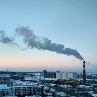 A wide shot of a city with a singular smoke stack pumping out smoke