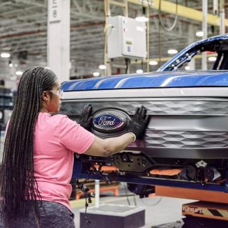 A Ford assembly worker putting a grill onto an electric Ford truck