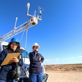 Scientists writing notes with truck in the background