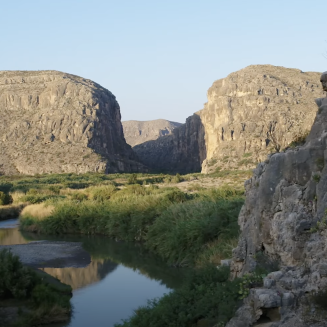 View of a river winding through rocky outcrops with a clear blue sky.