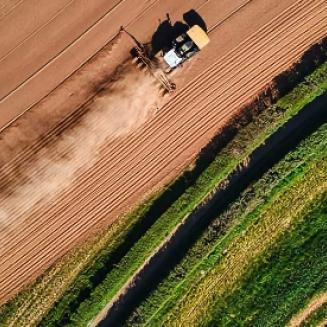 Aerial view of tractor rolling across a farm field