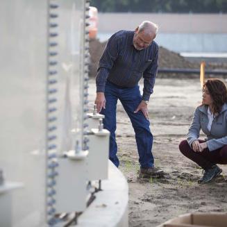 Two people examining a large curved structure outdoors.