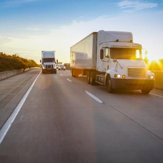 Clean trucks driving on a highway at sunset