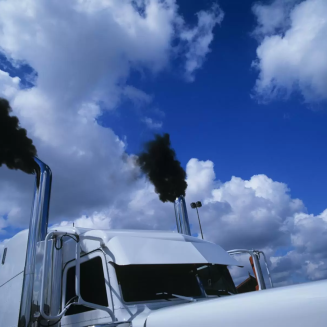 Diesel truck with black smoke coming out of exhaust pipes next to cab front