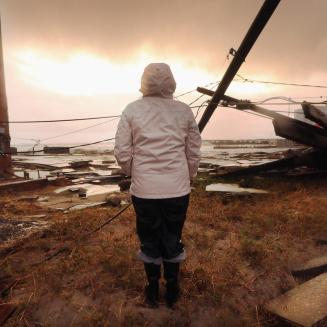 person looks out at destruction after a hurricane