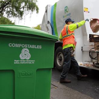 Recology worker Miguel Rojas throws a bag of compostable material into his truck
