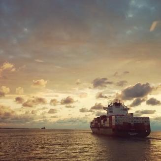 Container ship at sea with a colorful sky and clouds