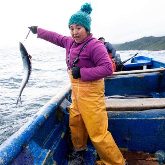 Woman fisher holds a fish on a line on a boat in northern Peru