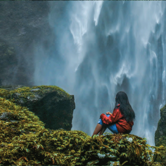 Girl on rock looking at waterfall