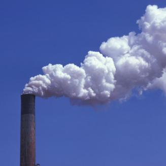 Smokestack emitting pollution into a blue sky.