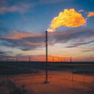 Methane flaring, with a flame burning bright against the sky.