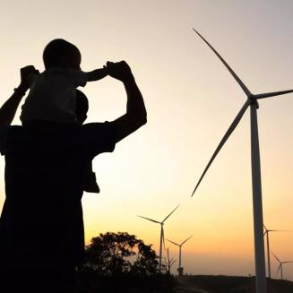 Adult and child looking joyful with windmills in the background.