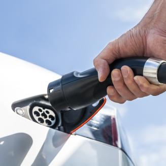 Close view of a hand plugging in an electric vehicle