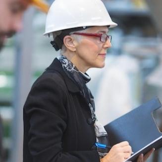 Woman wearing hard hat and business suit in a factory