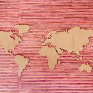 World map in brown paper against a pink background