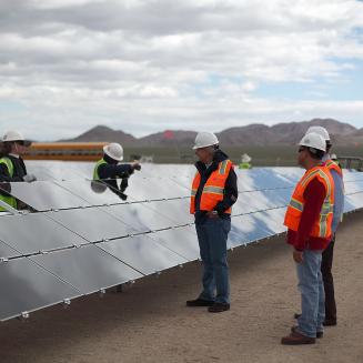 People in hard hats at a solar energy farm.