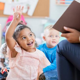 Little girl raising her hand in childcare facility
