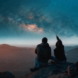 Two people on a mountaintop looking at the stars