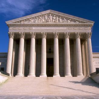 Supreme Court building, with majestic columns, under a blue sky.