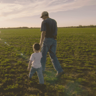 Father holding his son's hand and walking in a field