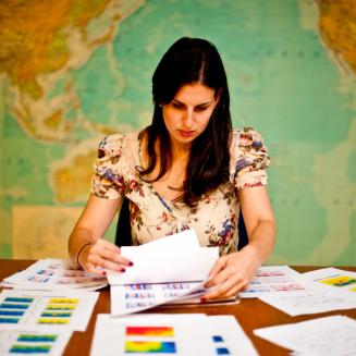 Woman looking at paperwork with a map of the world behind her