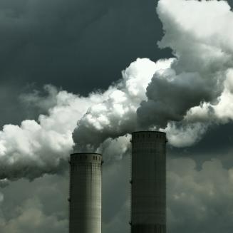 Smokestacks releasing emissions on a cloudy day.