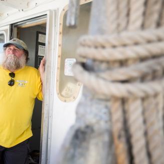 Keith “Buddy” Guindon standing at the door to a fishing boat with a rope tied up in the foreground