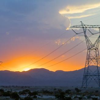 High-voltage transmission towers with sunset in the background