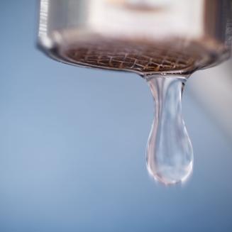 A drop of water coming out of a faucet.