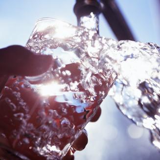Tap water flowing into a drinking glass.