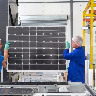 Two people carrying a solar panel