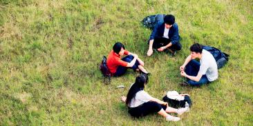 Four young people sitting in a field conversing