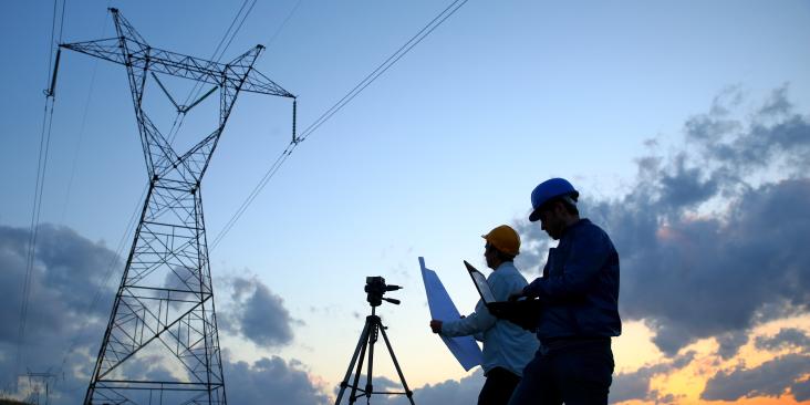 Surveyors overlooking powerlines at dusk