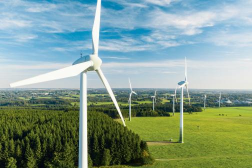 Wind turbines create clean energy against a vibrant blue sky and green landscape