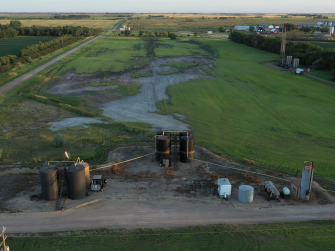 Aerial view of oil leaking from an abandoned well onto a green field in North Dakota