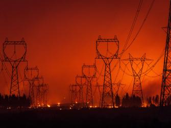 Transmission towers silhouetted by wildfire
