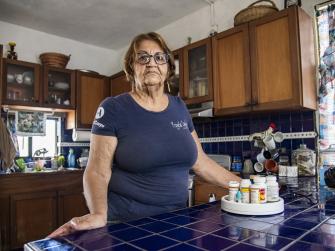 Veronica Melendez stands in her kitchen with her prescription medications on the counter.
