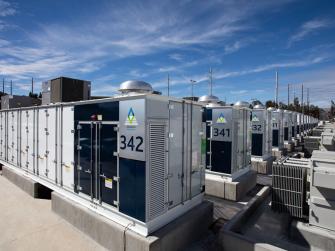 A row of battery storage units under a blue California sky