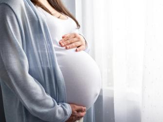 A pregnant woman cradles her belly