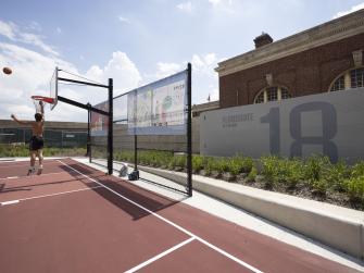 A person plays basketball on a basketball court with a moveable floodgate behind it