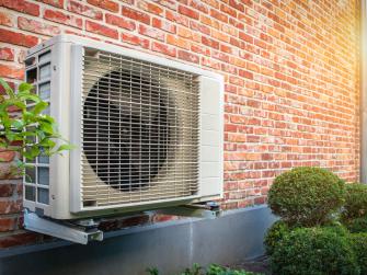 A heat pump installed next to a brick wall
