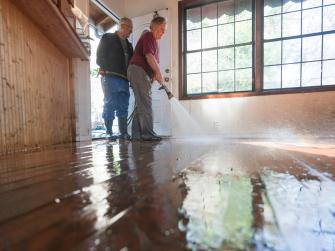 Two people power washing floors after flood damage