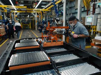 An Automated Worker On An Assembly Line Working On Electric Vehicle Components