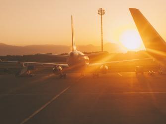 Planes on a runway with a very hot-looking sun on the horizon behind them