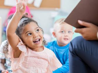 Little girl raising her hand in childcare facility
