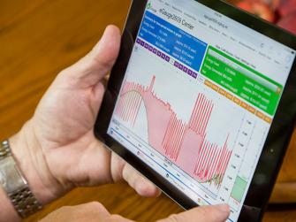 A left hand holding a tablet with a right hand pointer finger pointing at the screen